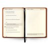 Ambassador Journal open to a daily page — the 5/5/5 rhythm with morning, midday and end-of-day prompts, facing a dot-grid notes page